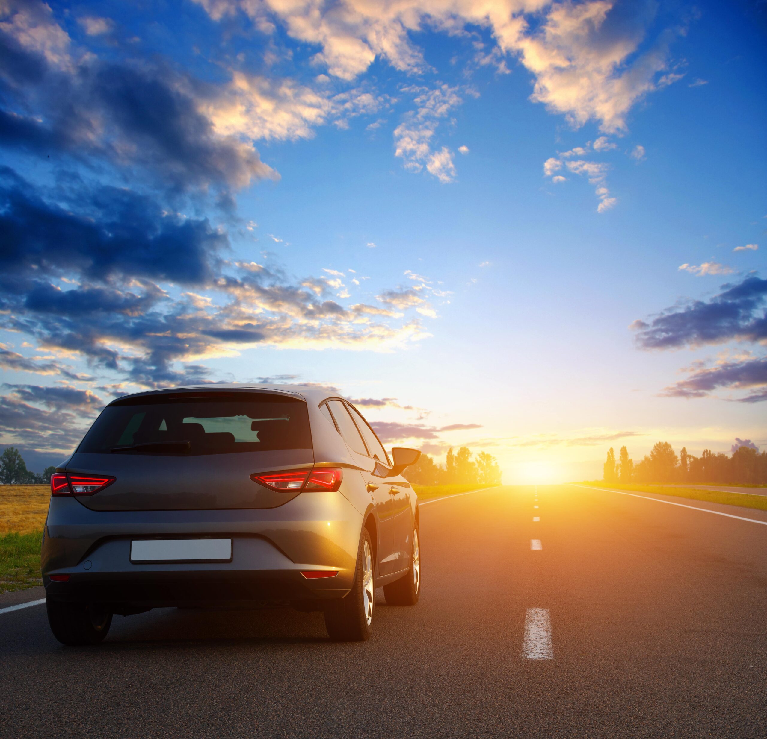 hatchback driving into the sunset along a road