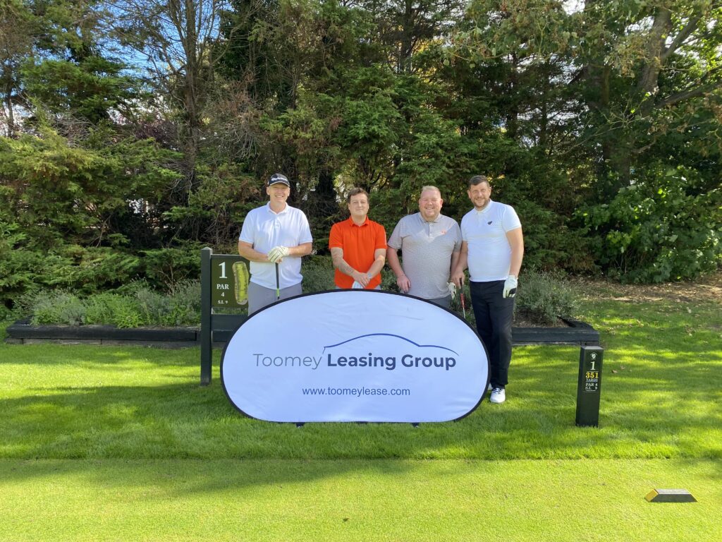 Clients on the Golf field standing behind the Toomey Leasing Group banner