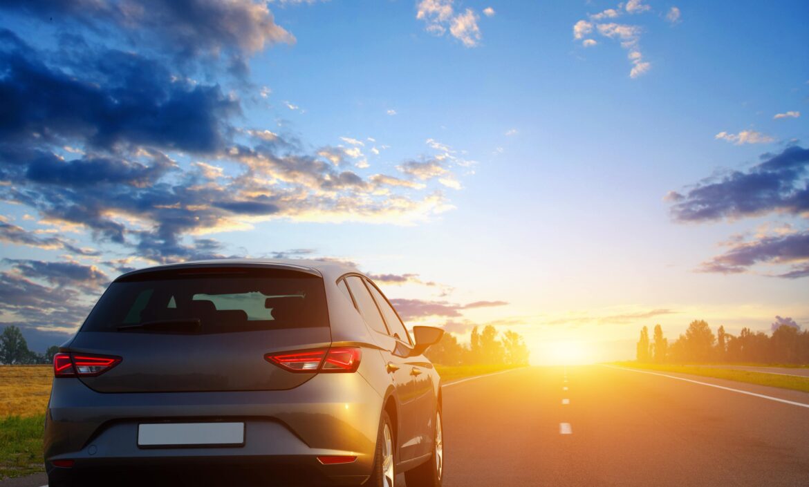 hatchback driving into the sunset along a road