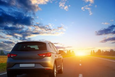 hatchback driving into the sunset along a road